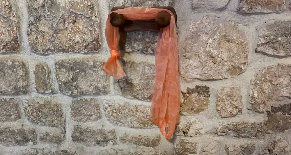 The first homemade Fähloo, a plain coral mesh knotted at one end, draped over a wooden peg in Dubrovnik, June 2023