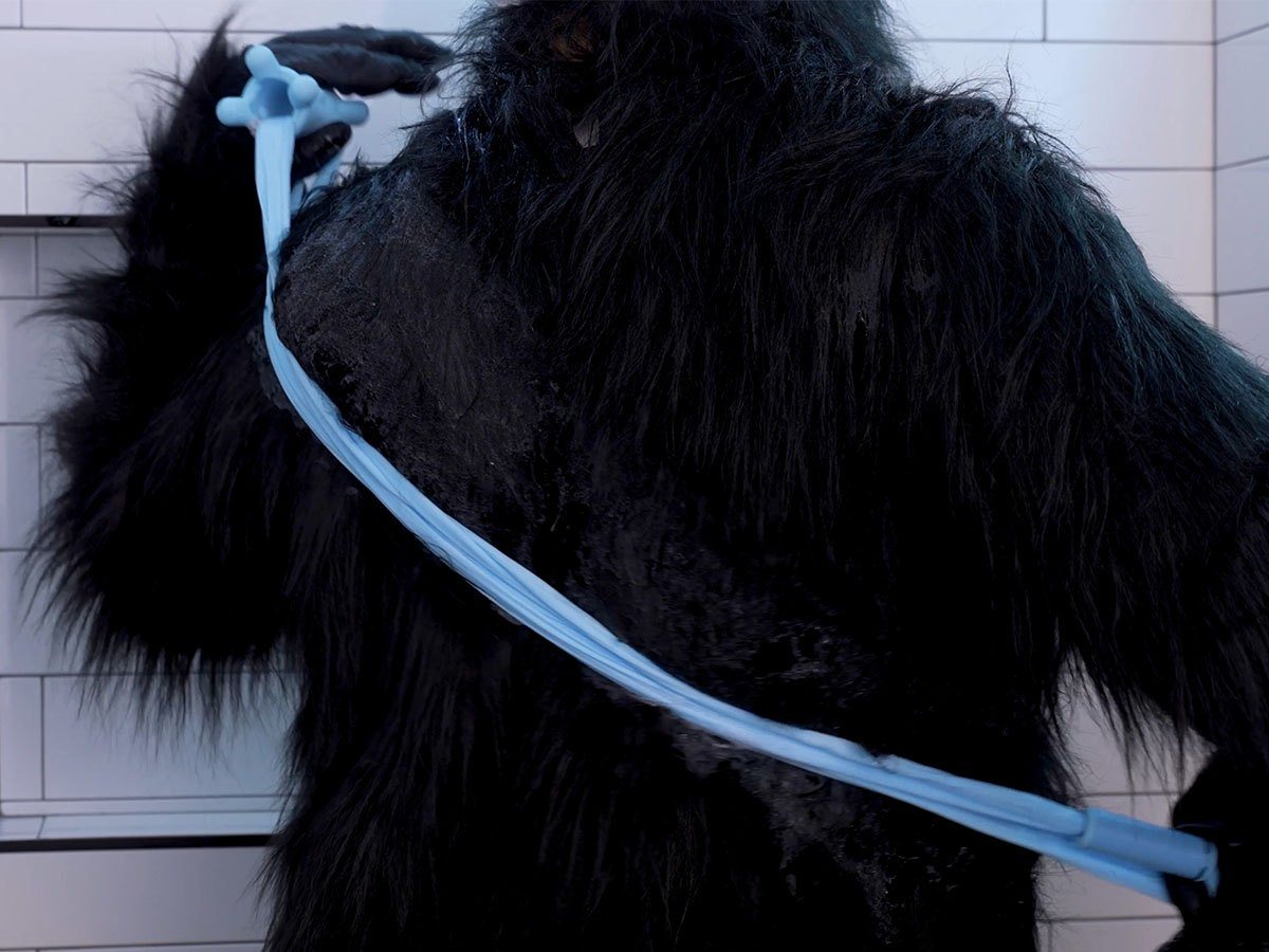 Gorilla holding one Fähloo handle by his shoulder, the blue mesh extended diagonally across his back