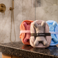 Three Fähloo exfoliating bathing meshes on a spa shower counter